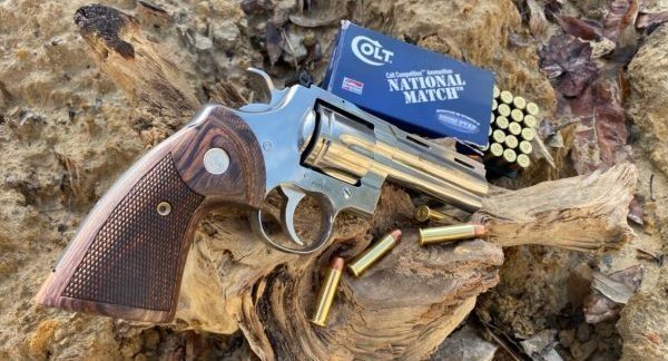 Colt Python revolver on deadwood log with Colt ammunition box