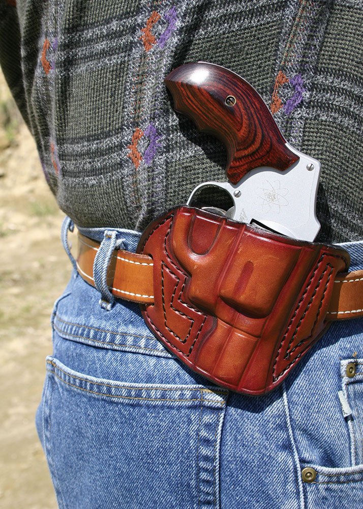 revolver in a leather holster worn on a belt at the small of the back position