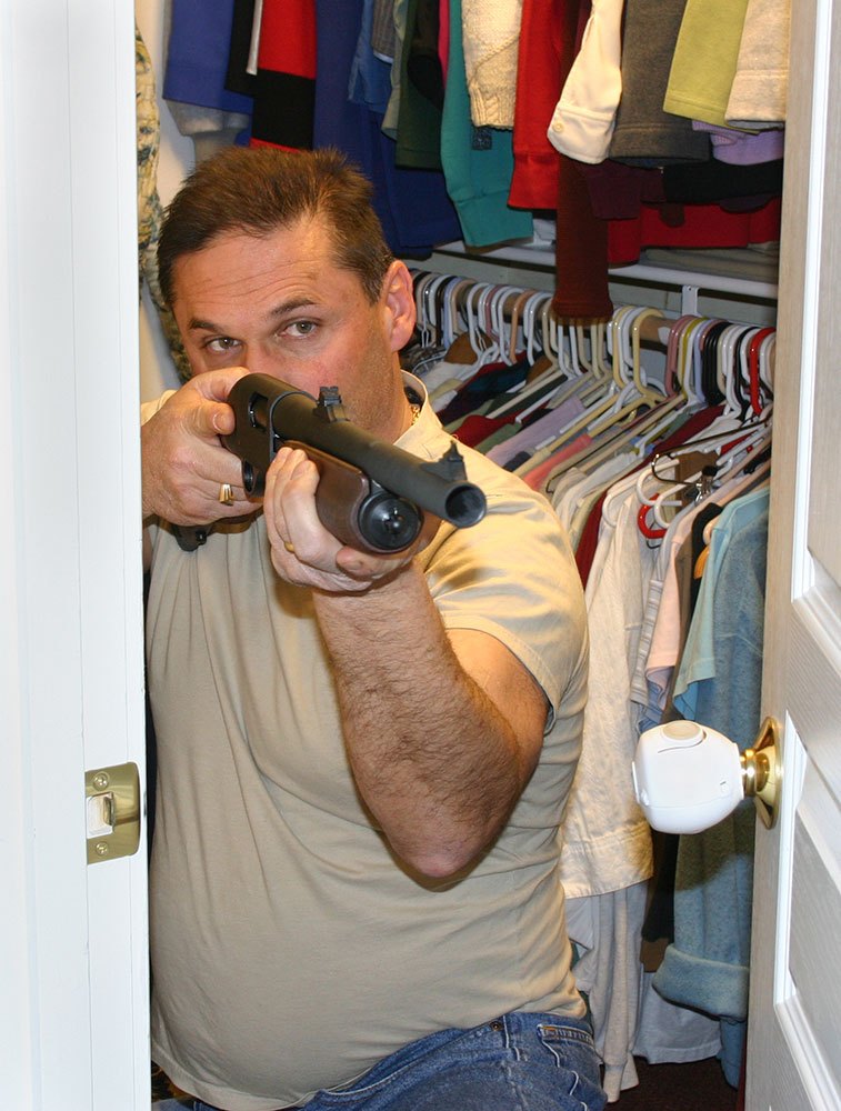 Man hiding in a closet with a shotgun pointed out of the door