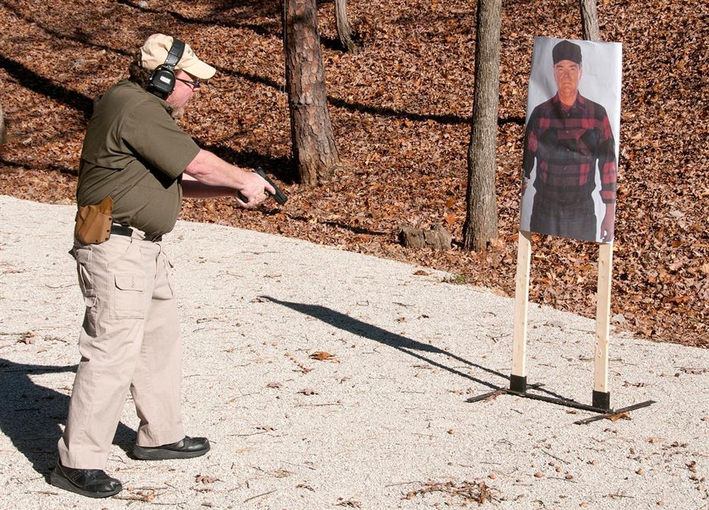 David Kenik inting a handgun at the ground in front of a target