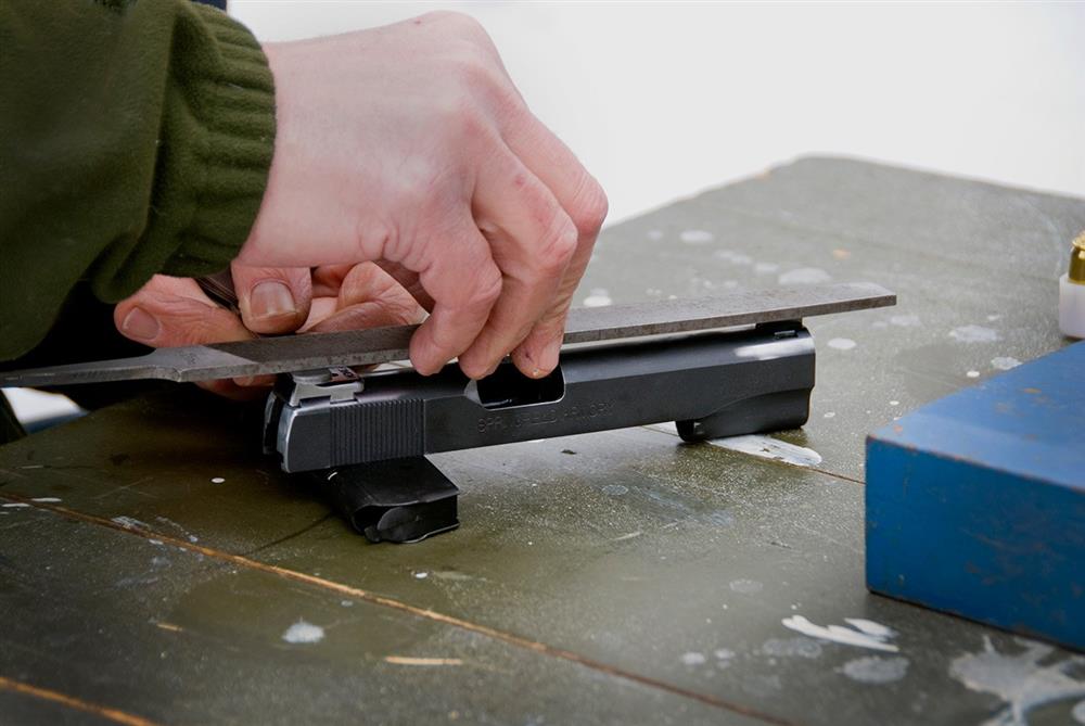 1911 pistol slide with a file set atop of the sights for adjustment