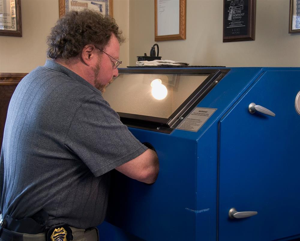 David Kenik working on a pistol in a sandblasting machine