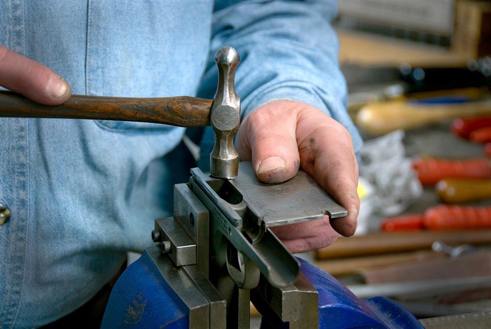 Fitting the slide to the frame of a 1911 pistol with a small hammer, close up