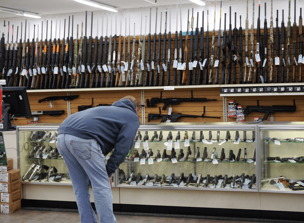 Man looking into glass counter display at handguns