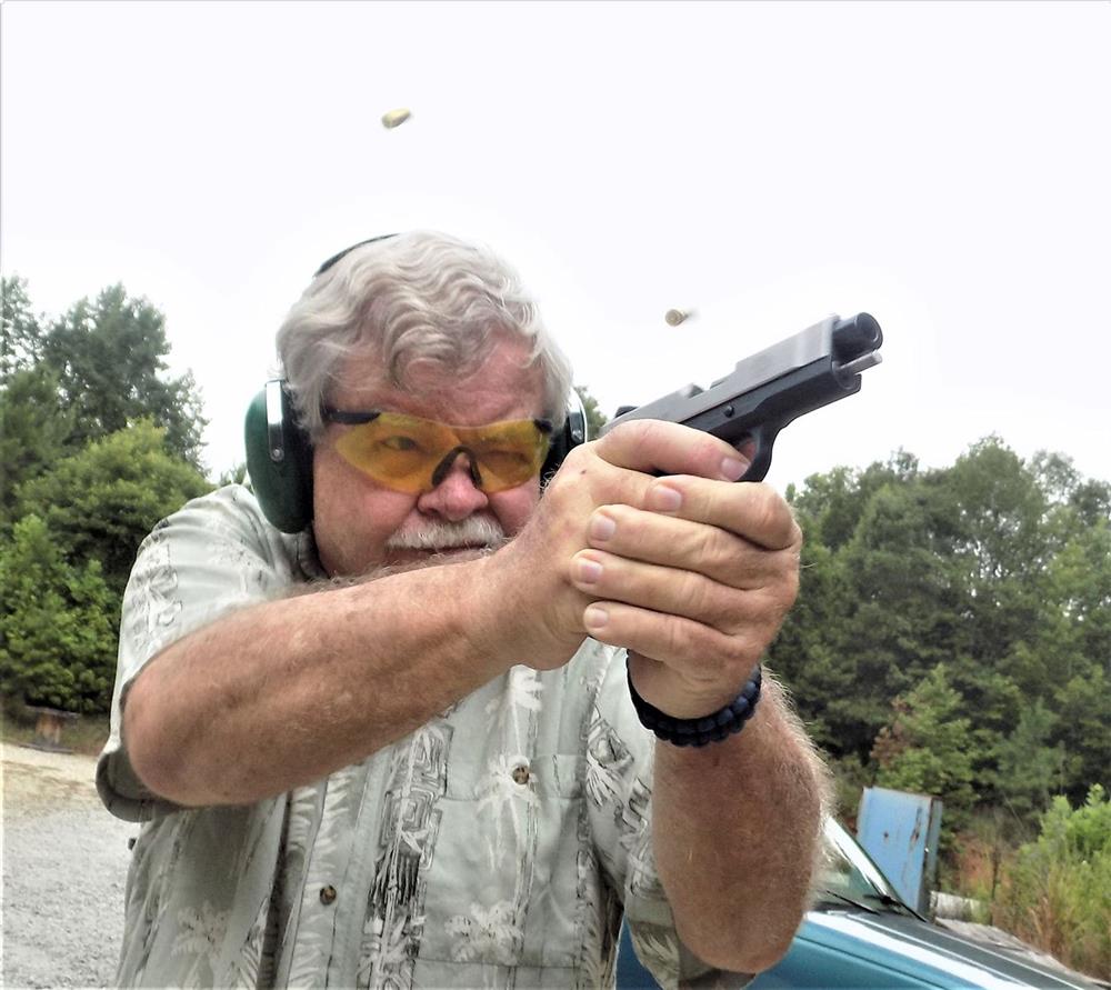 Bob Cambell shooting a pistol with spent cartridge cases in the air 